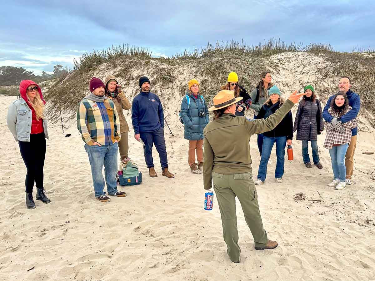 Erika Delemarre  - Volunteer Coordinator for Monterey Surfrider Chapter, explains to participants standing on the Asilomar beach about dune ecology. Photo: Harry Parker