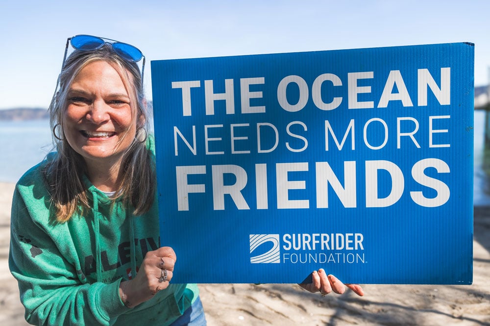 Kelly Jones With the Surfrider South Sound Chapter holding a sign that reads "The Ocean Needs More Friends"