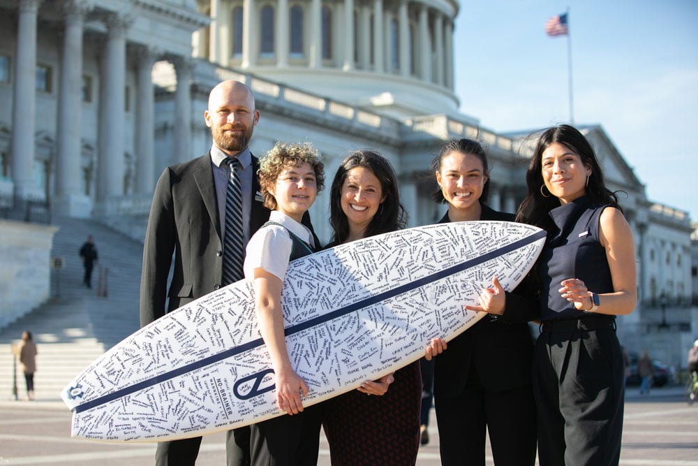Surfrider Activist Bethany Case with San Diego Chapter holding a surfboard on Capitol Hill for Surfrider's annual coastal Recreation Hill Day 