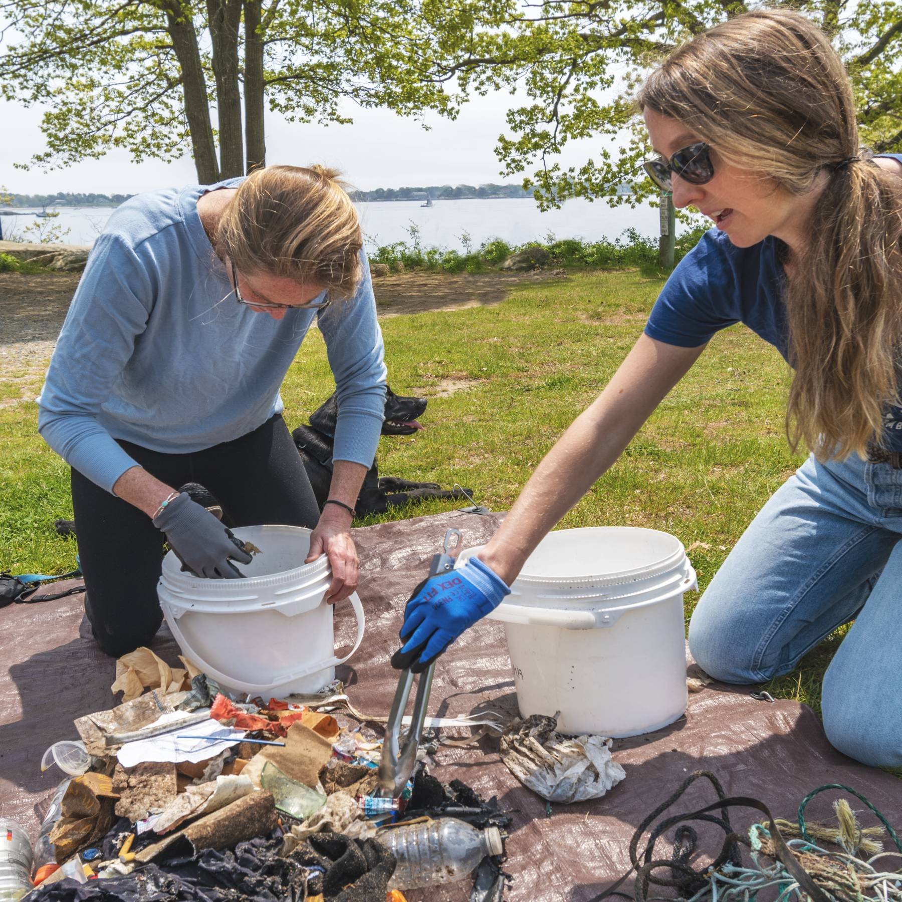 Two volunteers sort trash from a cleanup