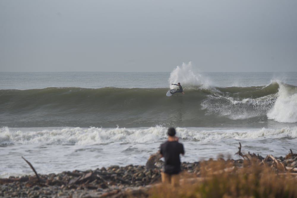 A surfer does a powerful carve on a large wave at Surfers' Point.