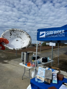 A used styrofoam bowl held out in front of a surfrider canopy under a blue sky with white clouds