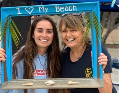 Volunteers posing with a wooden picture frame that reads "I <3 my beach"