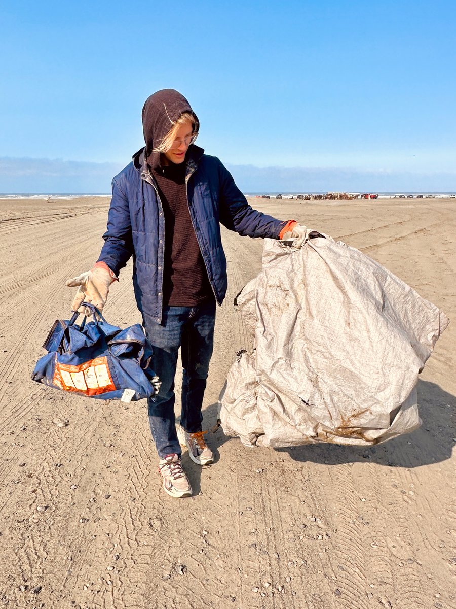 Male volunteer holding up trash he found during a beach cleanup at the Pacific Coast