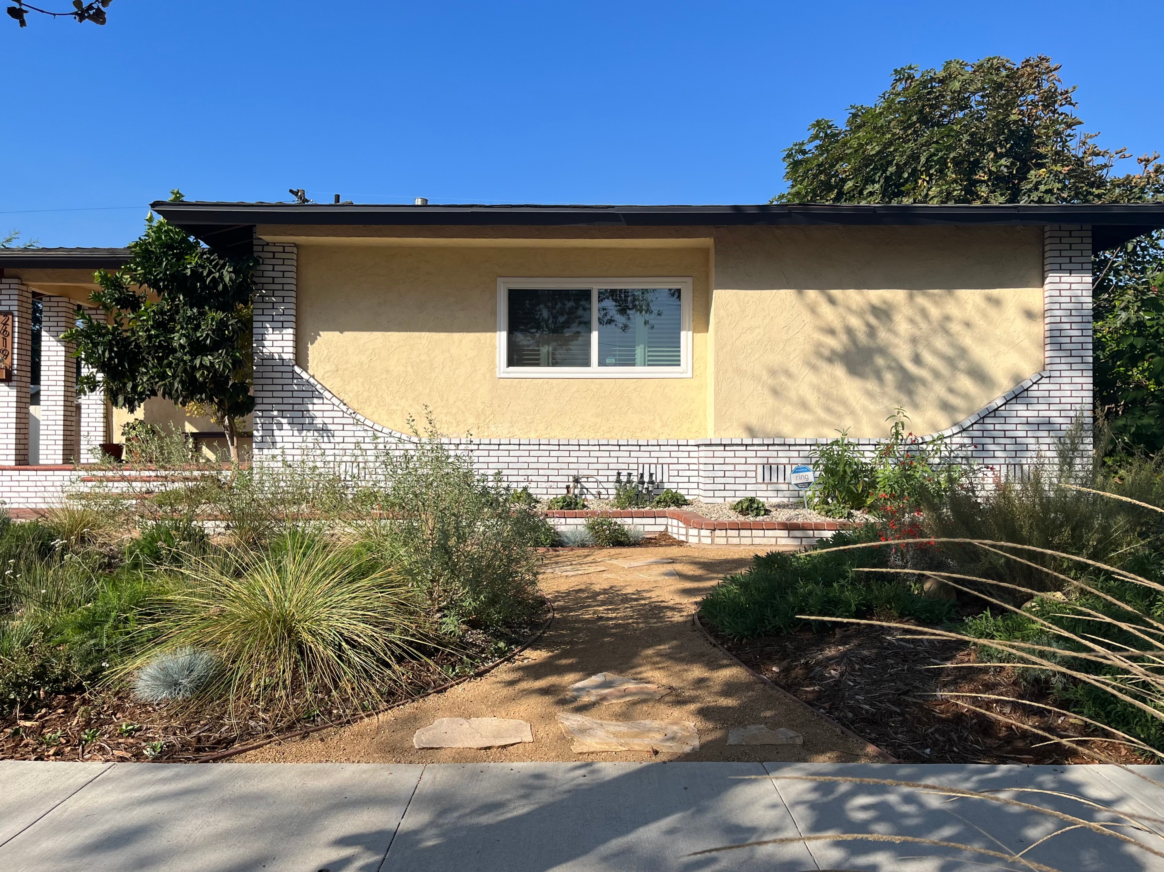 A yellow house with native plant landscaping and a flagstone pathway