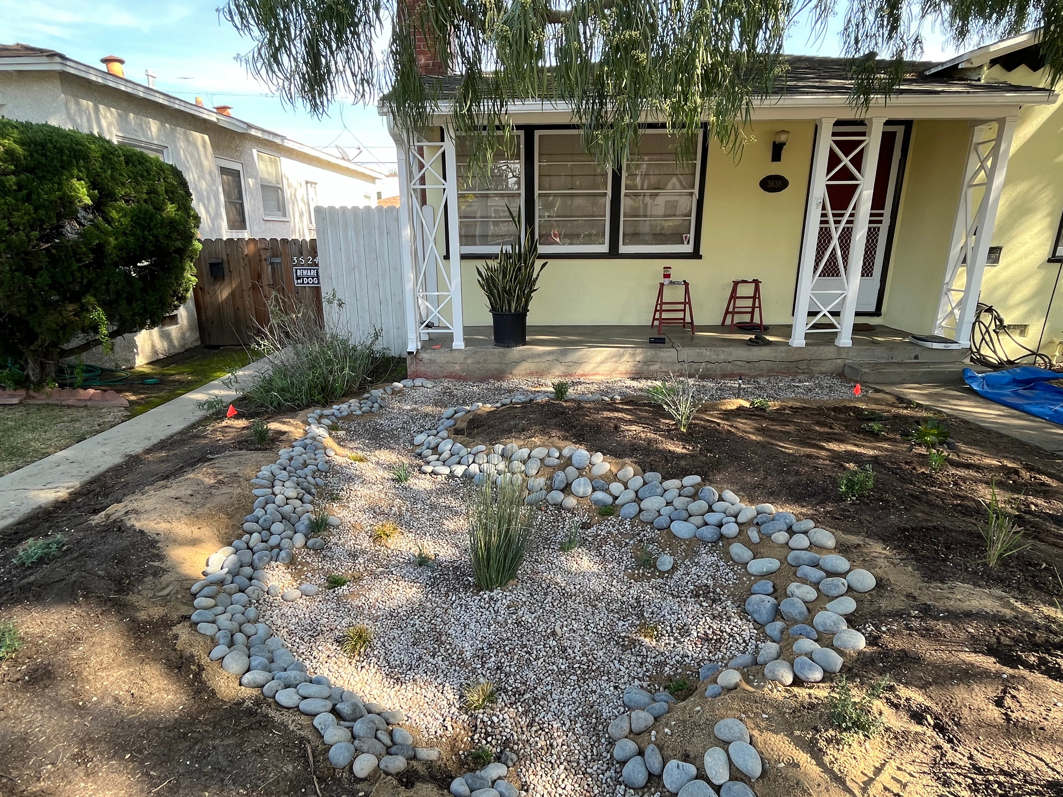 a yellow house with a rain garden in the front