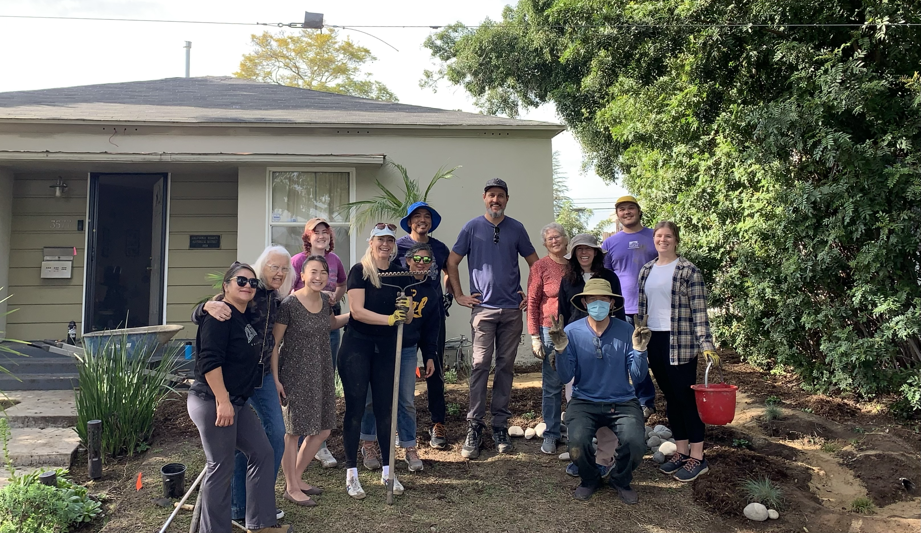 a group of people with garden tools stand in front of a home in Long Beach California