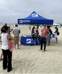 Surfrider Easy up tent on the beach and people standing around it