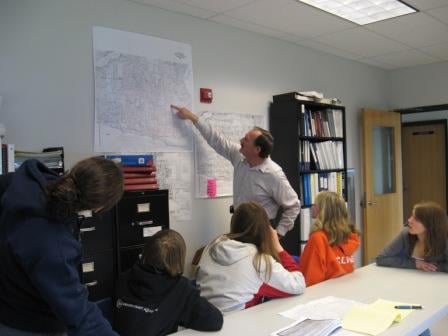 Youth volunteers review stormwater maps with a city engineer in Newport 