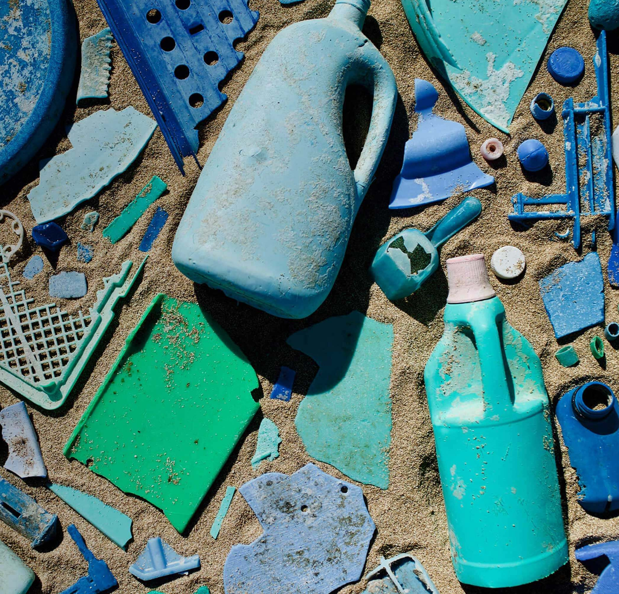 blue plastic pieces are layed out to create a featureless mosiac on top of sand.