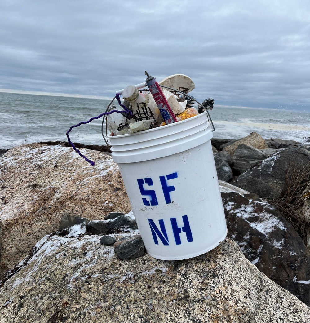 A bucket full of trash at a Surfrider New Hampshire beach cleanup