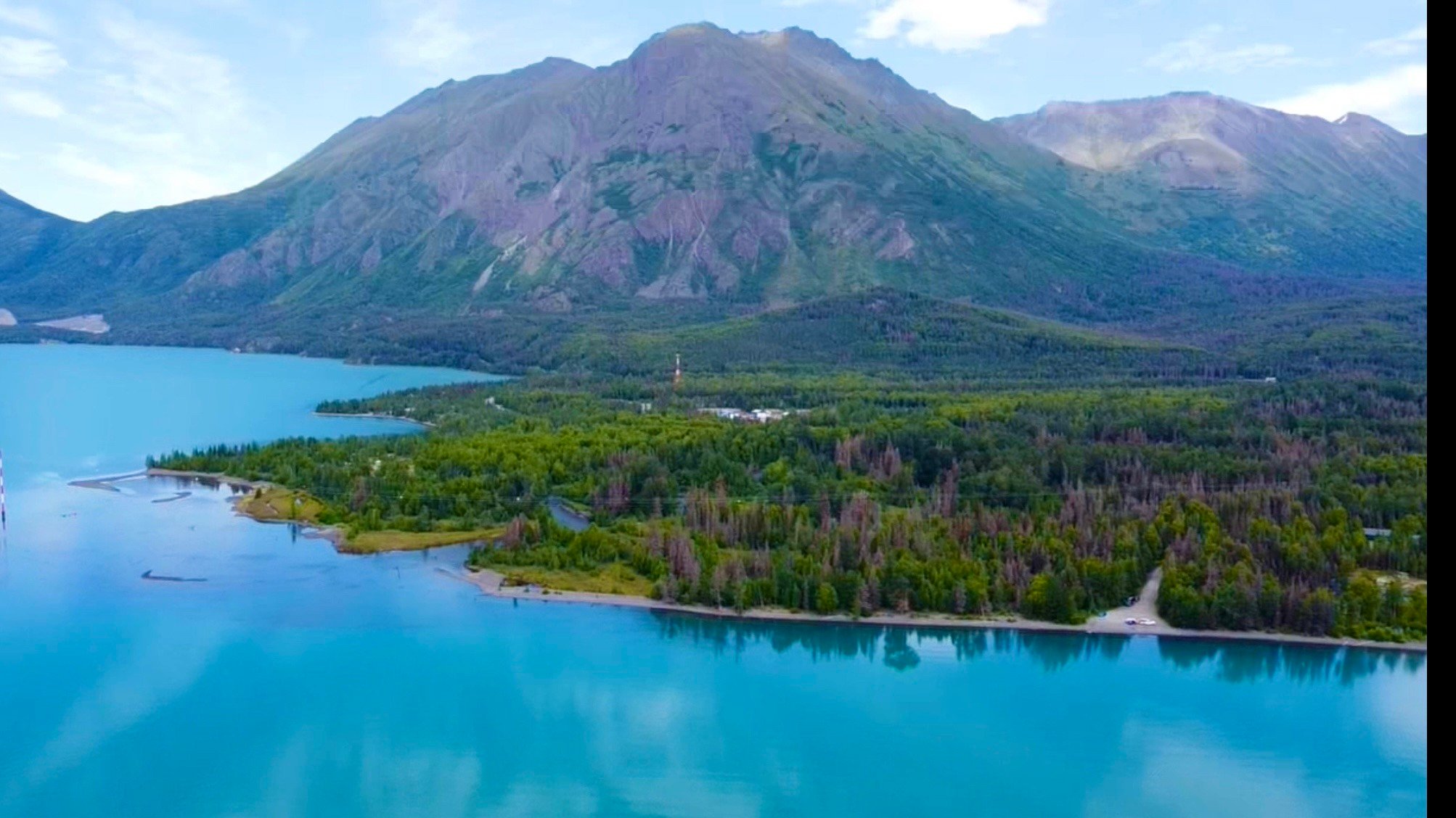 Drone shot of the blue Kenai River with green mountainous backdrop