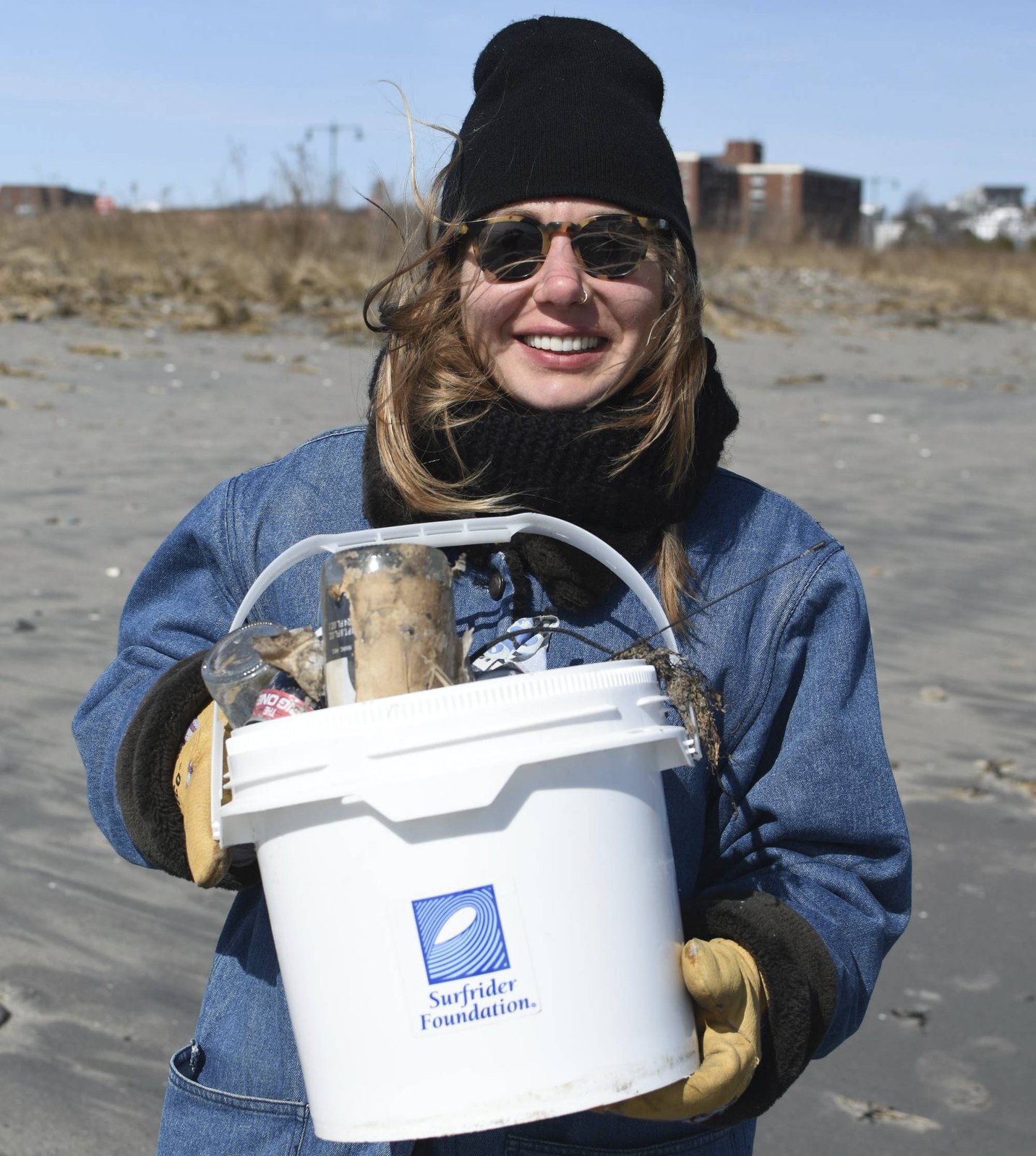 Volunteer posing with bucket of trash found at cleanup