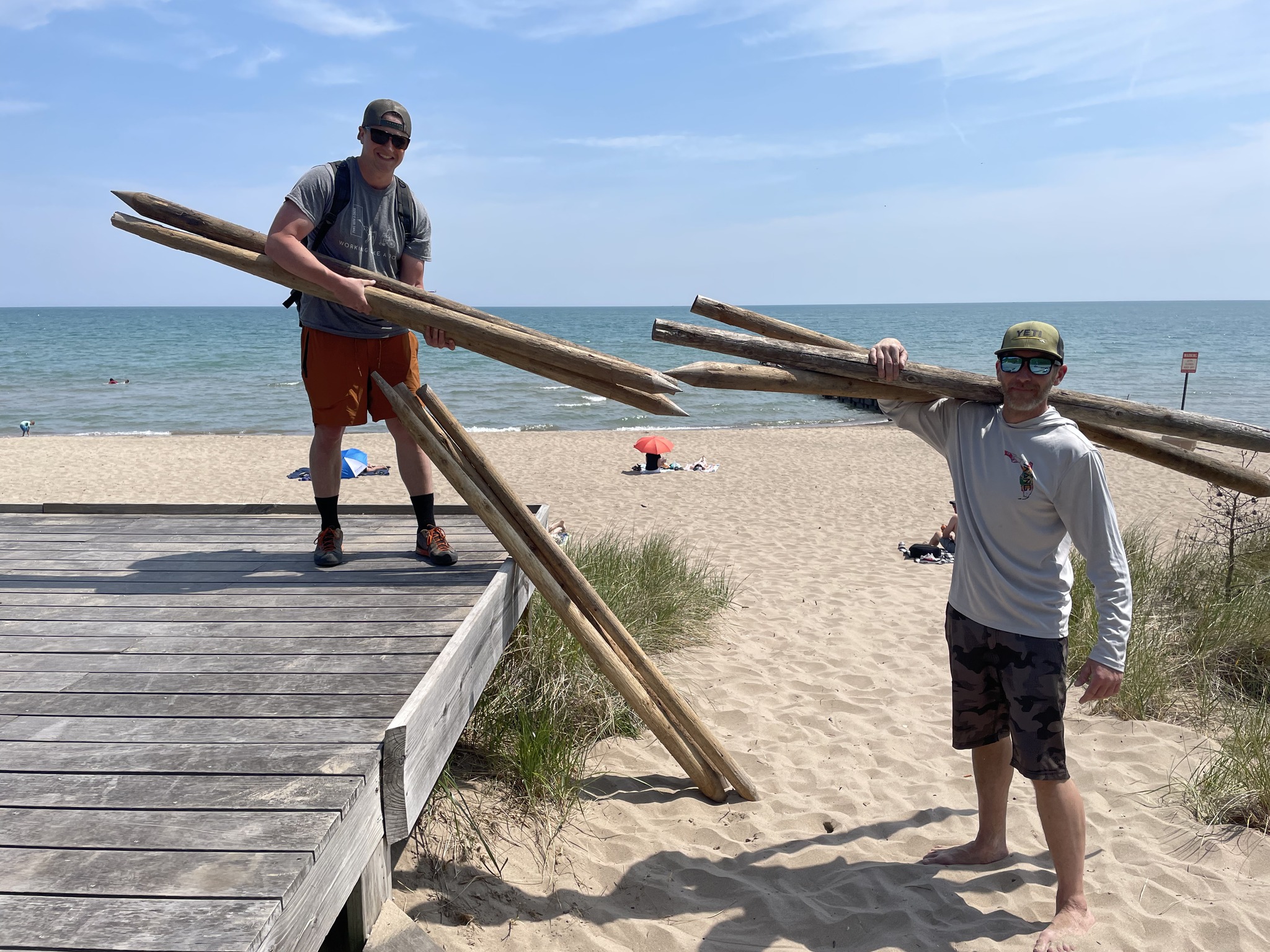 MKE dune restoration volunteers carrying posts