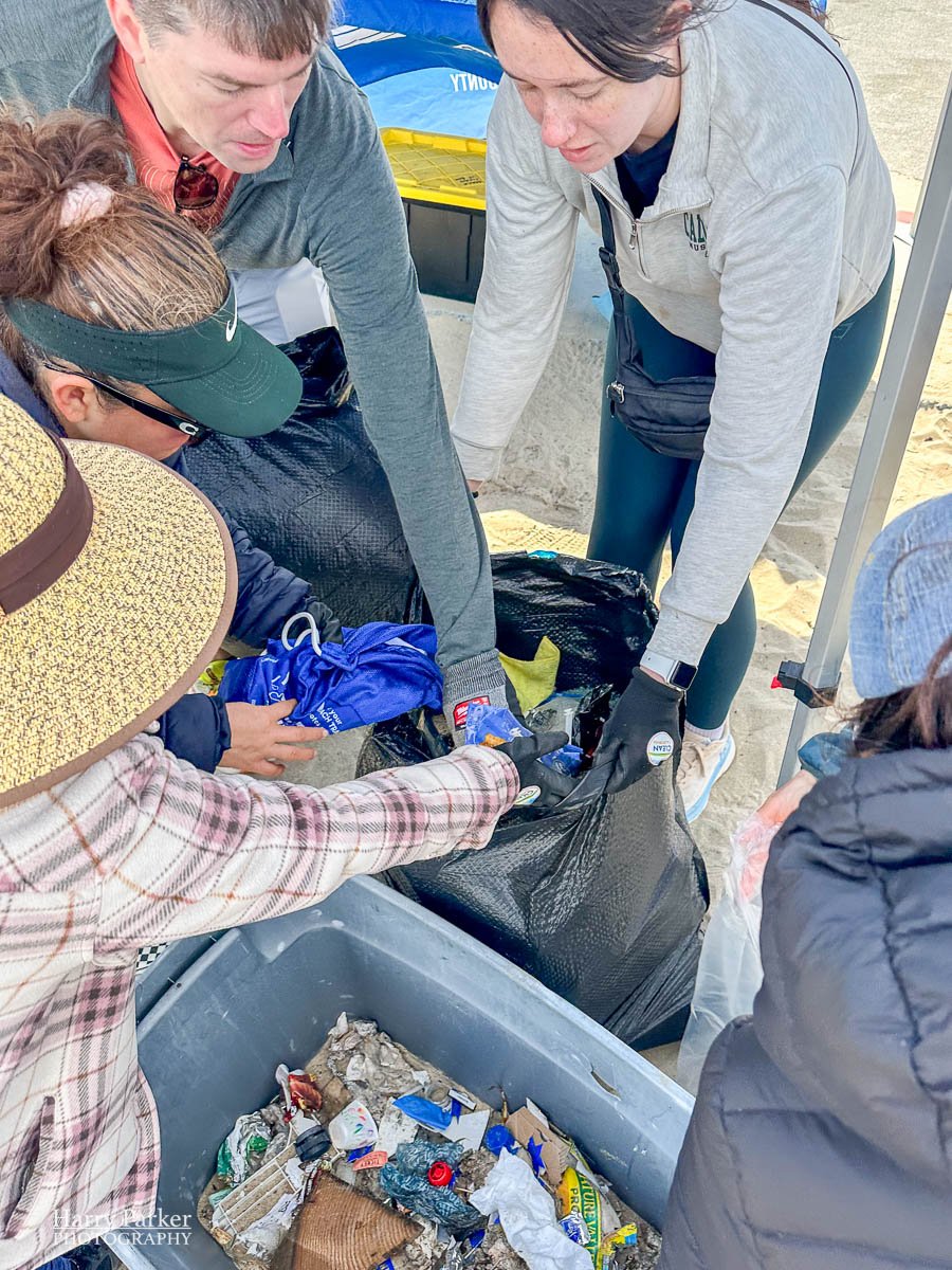 Volunteers all reach into a pile of garbage for sorting.