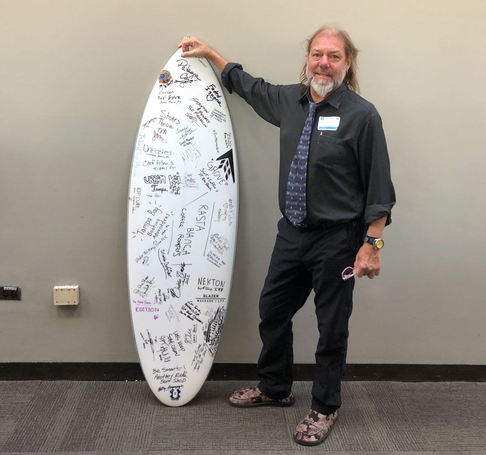 Steve Arman with the Chicago Surfrider Chapter holding a signed surfboard at Surfrider Coastal Recreation Hill day in Washington D.C