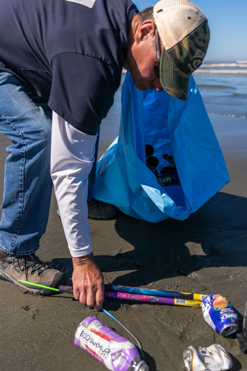 Volunteer picking up trash by water-1