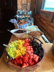 A breakfast buffett with fresh fruit, bowls of granola and yogurt, and fresh baked goods