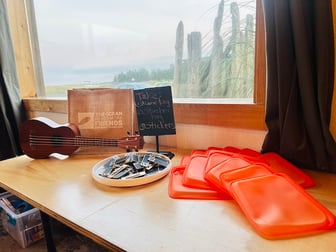 The entry table display of bright orange Stasher bags, reusable chalk name tags, a rustic Ocean Needs More Friends bag, and a ukelele