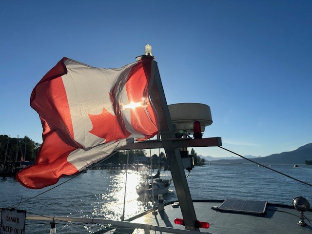 The Canada flag waiving in the setting sun with Vancouver Harbor in the background