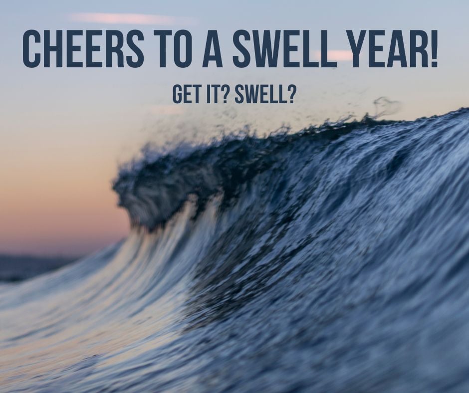 A smooth wave breaking at sunset with the words Cheers to a swell year - get it? Swell?