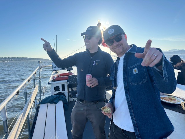 Surfrider Canada crew smiling on a sunset cruise with the Canadian flag in the background