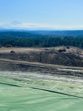 A sprawling green liner laid over a hill with active landfill in the background