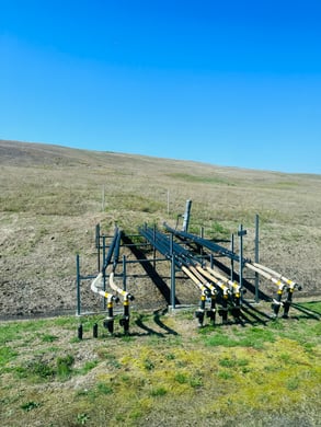 Black pipes jutting out of the base of the hill of an inactive landfill 