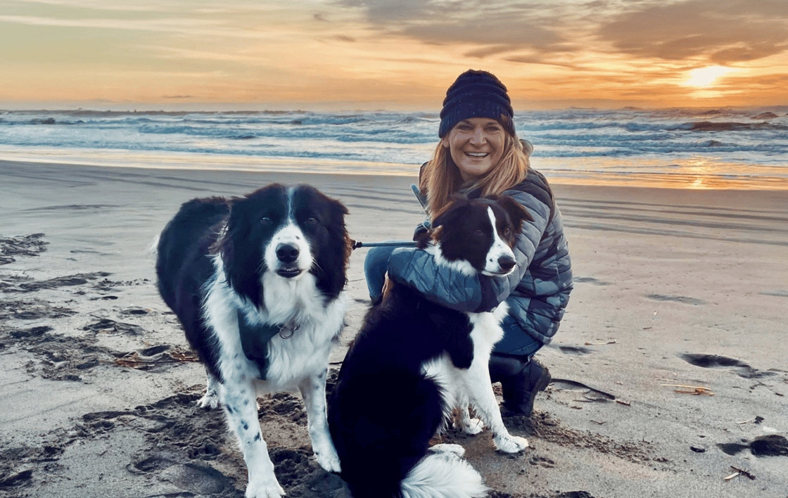 Kelly bundles up on a sunset beach posing with her two dogs