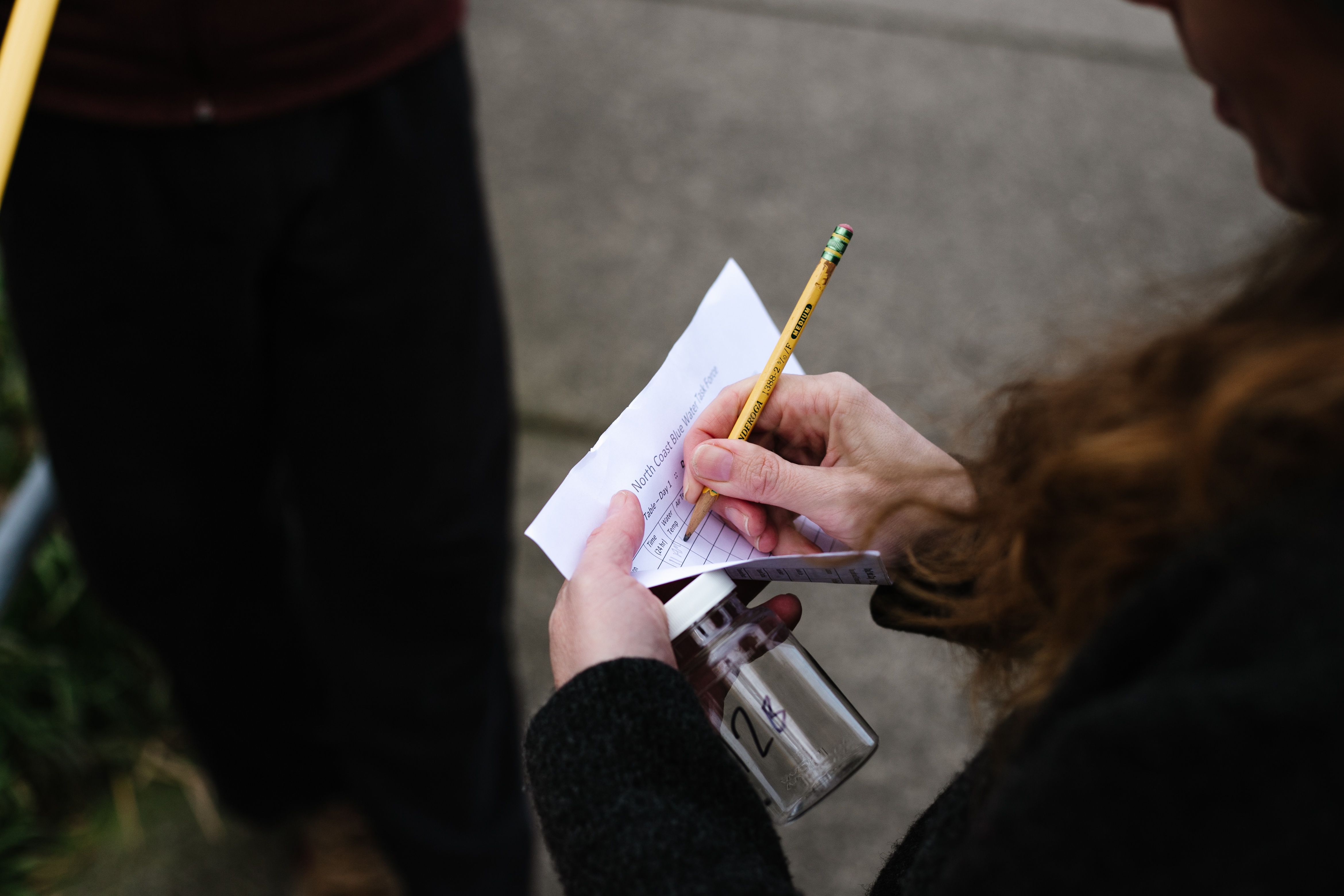 A volunteer take notes as they sample water to be tested