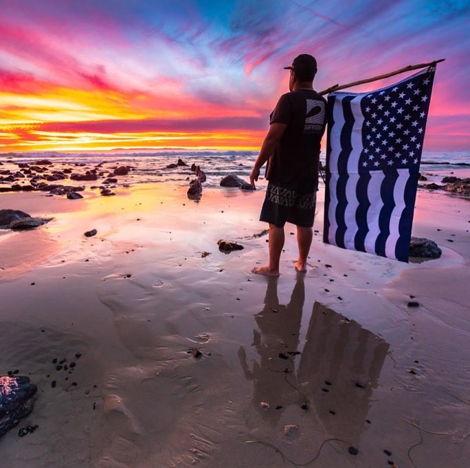 Holding Surfrider flag in front of sunset