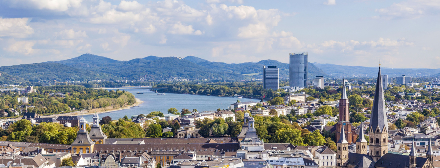 Skyline of Bonn, Germany with mountains and river in the distance.