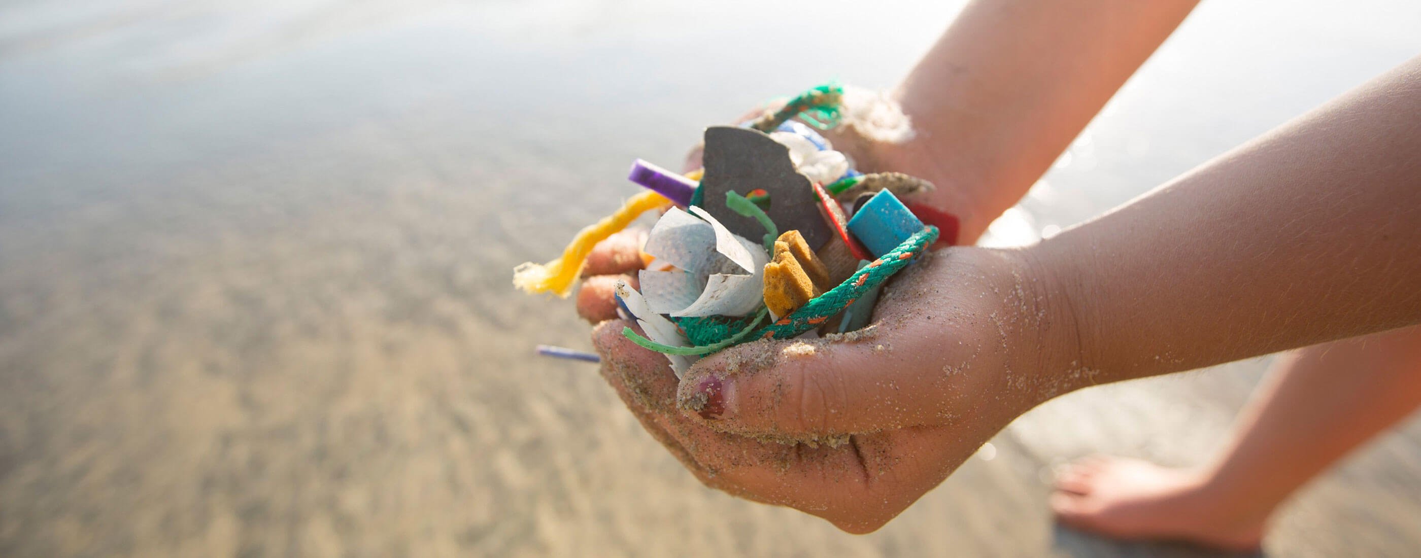 child's hands holding plastic trash collected from the beach