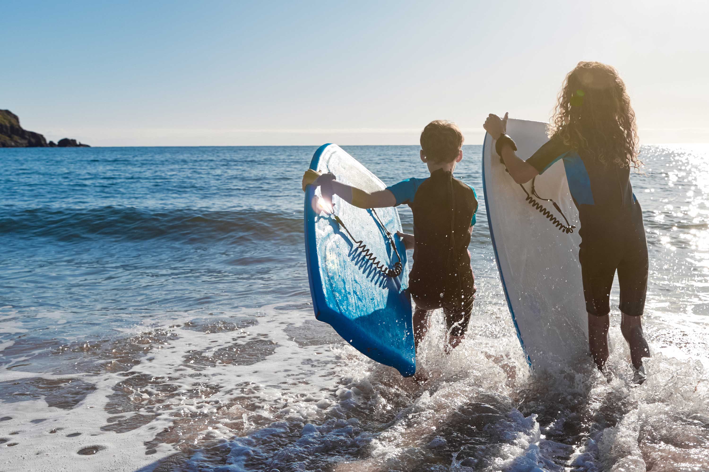  Two children walking into the water with their boards