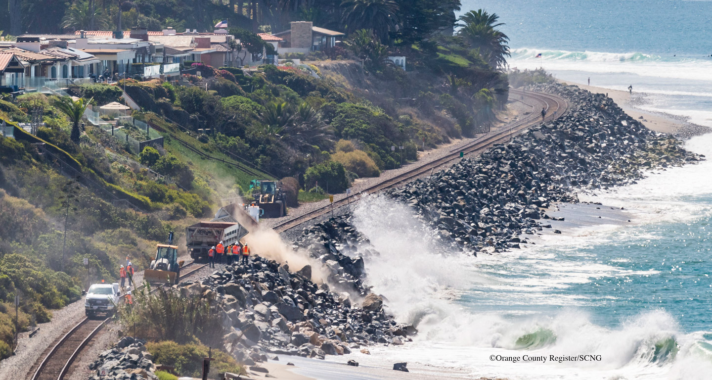 Workers add rocks to the shoreline in San Clemente, California to help protect the train tracks from falling into the ocean