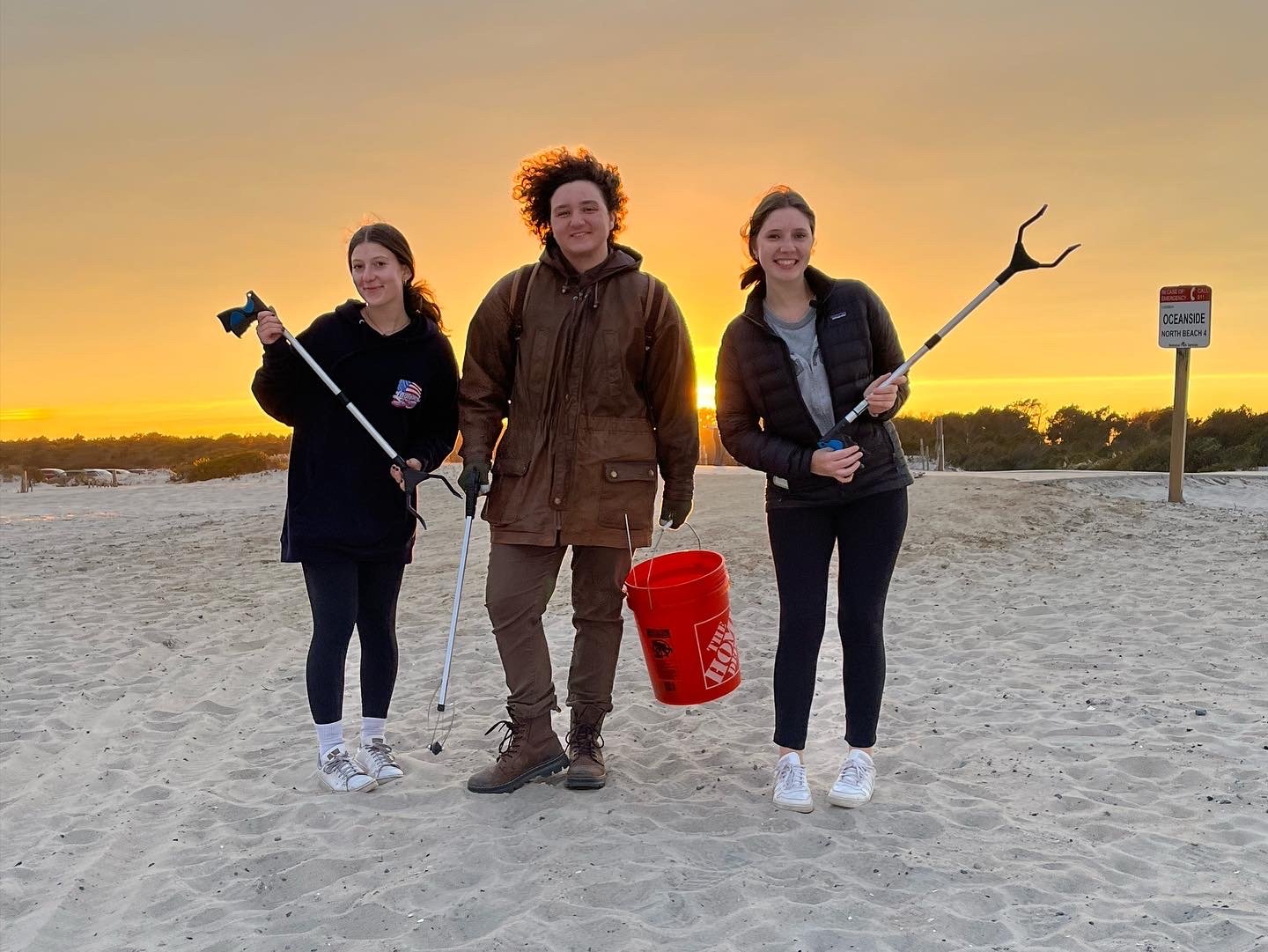 Three young beach clean up volunteers smiling