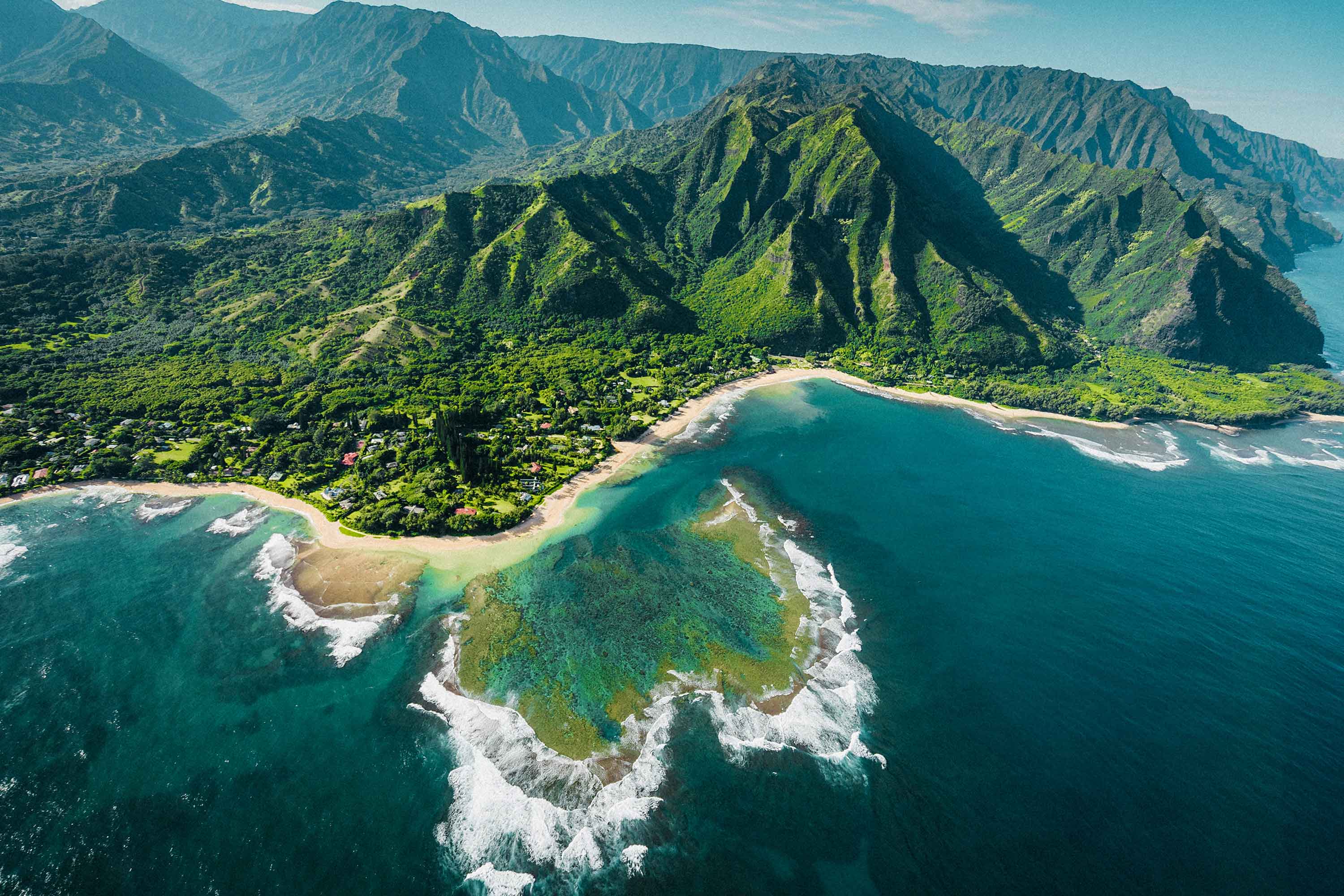 Arial shot of the Hawaiian coast with the island in the background and ocean in the foreground.