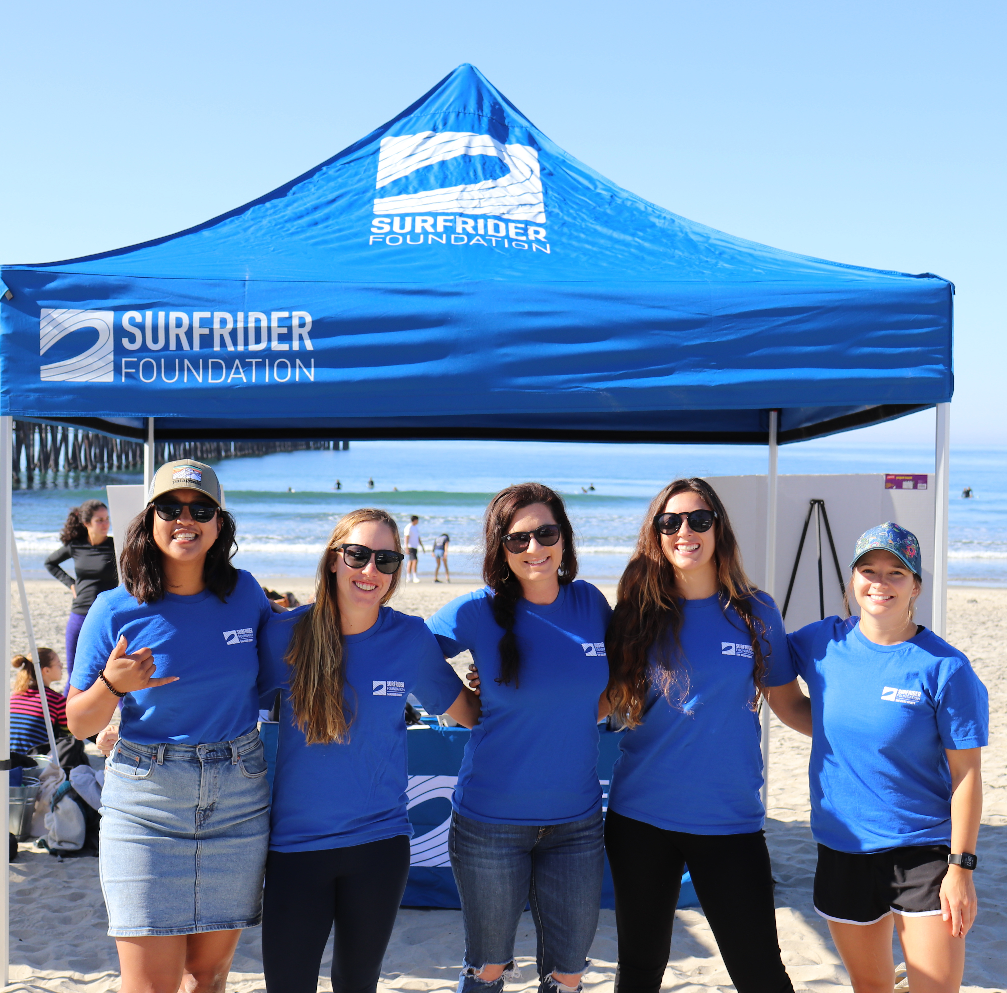 blue water task force committee leads standing in front of a blue surfrider tent