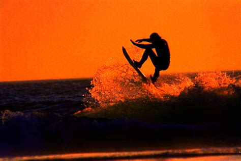 An artistic retro silhouette of a surfer launching off the top of a wave