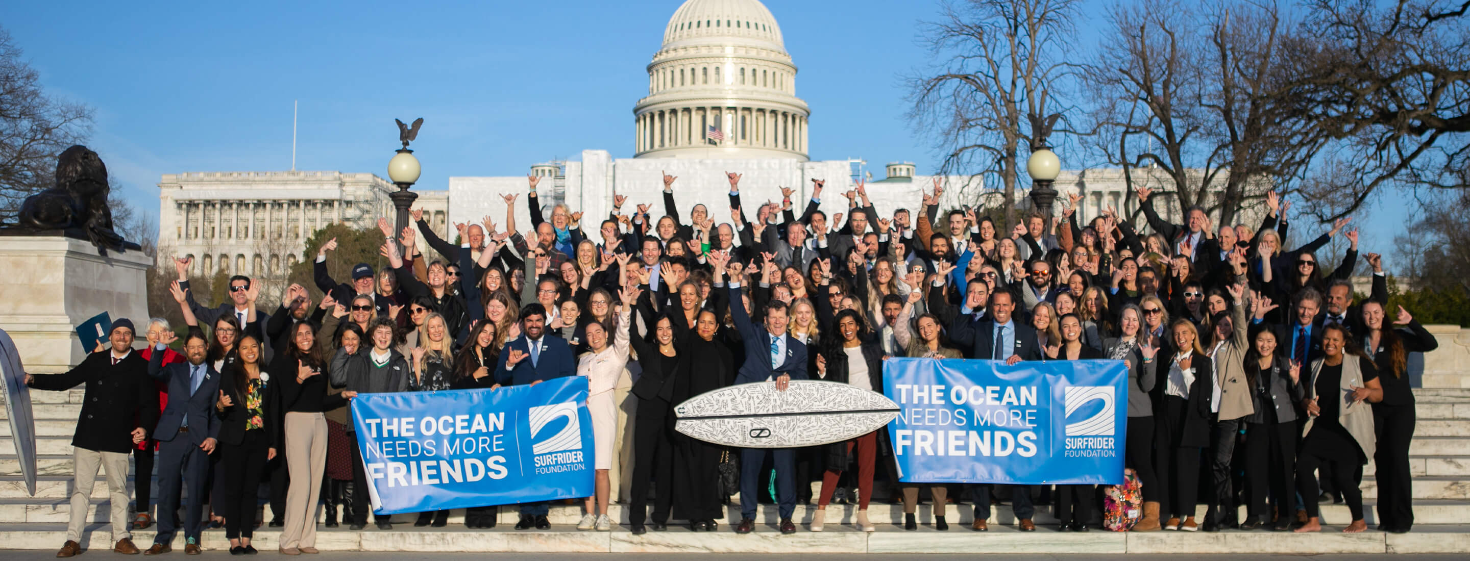 a group of finely dressed Surfrider volunteers and staff cheer in front of the Capitol in Washington DC