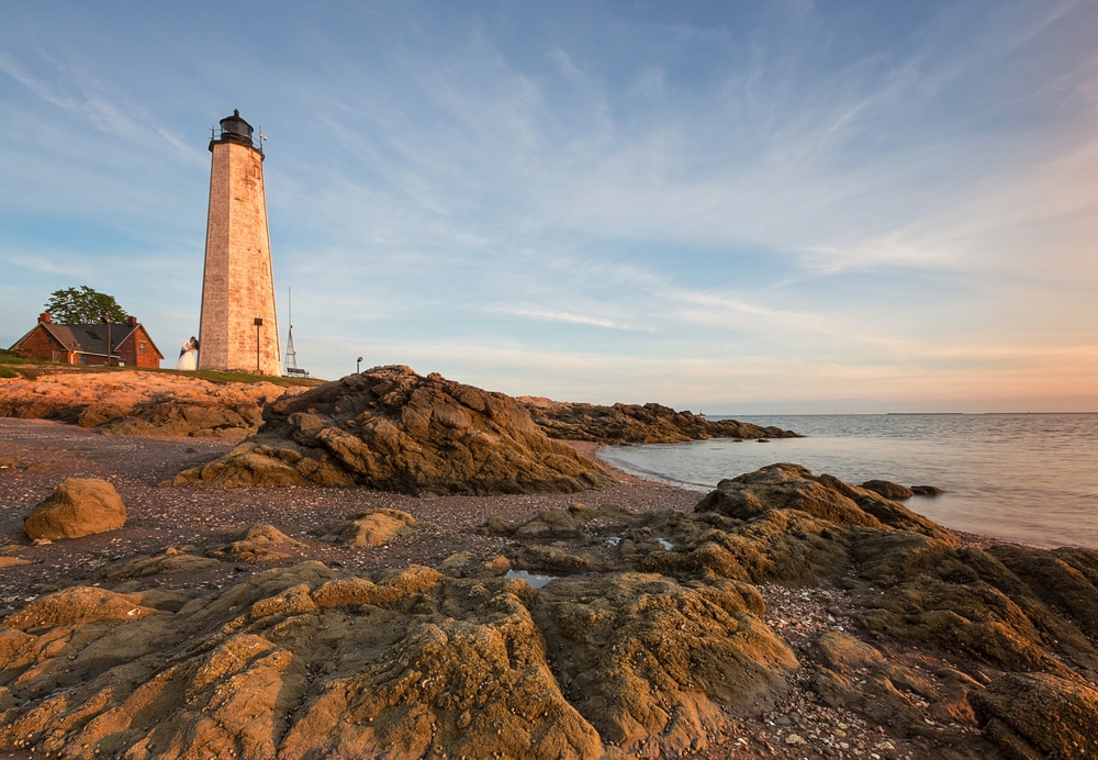 CT lighthouse on rocky shore at sunset